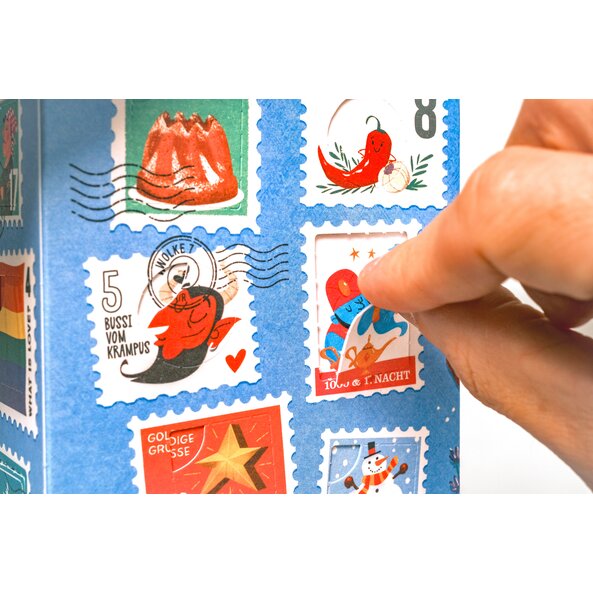 Hand öffnet ein Fensterchen des Gewürz Adventkalenders mit festlichen Briefmarkenmotiven