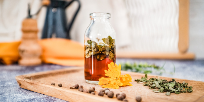 Kräuteressig Zitronenmelisse | © SONNENTOR Auf dem Foto sieht man eine Flasche mit Kräuteressig. Darin sieht man Zitronenmelisse. | © SONNENTOR