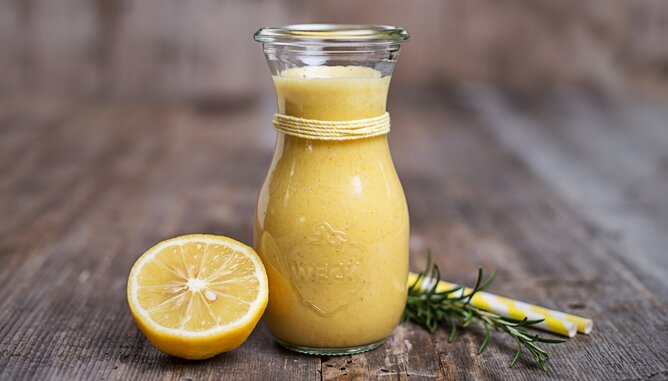 Smoothie | © SONNENTOR Auf dem Foto sieht man eine Flasche mit gelben Smoothie. Daneben sieht man eine Zitronenscheibe und Rosmarin. | © SONNENTOR