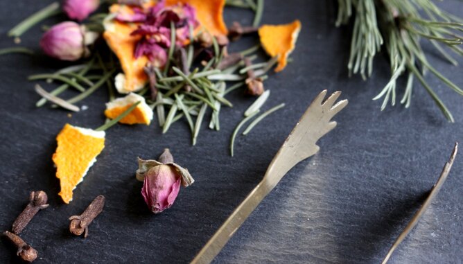 Jarolim Räuchern Laune | © SONNENTOR Auf dem Foto sind Nelken, Rosmarin, Rosenblätter und Orangenschalen zu sehen. Daneben liegt eine Räucherzange. | © SONNENTOR